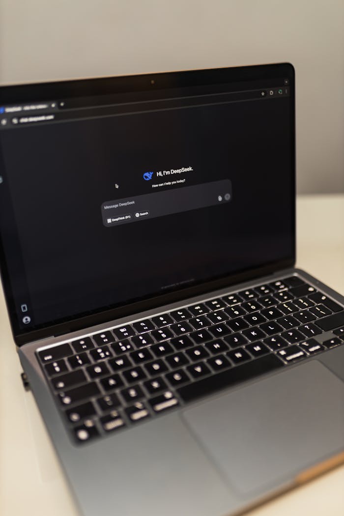 Close-up of a laptop showing an AI chat interface in a dimly lit room.